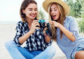 dois feliz fêmea amigos, entusiasmado modelo com dela pessoal fotógrafo . foto