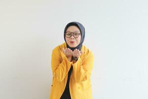 jovem lindo ásia muçulmano mulher, vestindo óculos e amarelo blazer com feliz sorridente face expressão foto