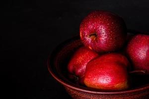 Suculenta maçã vermelha fresca com gotas de água contra um fundo escuro foto