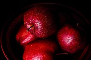 Suculenta maçã vermelha fresca com gotas de água contra um fundo escuro