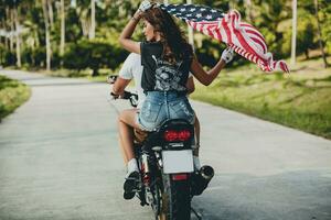 jovem casal dentro amor, equitação uma motocicleta, abraço, paixão, livre espírito, americano bandeira foto