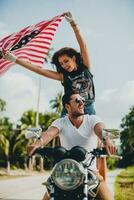 jovem casal dentro amor, equitação uma motocicleta, abraço, paixão, livre espírito, americano bandeira foto