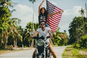 jovem casal dentro amor, equitação uma motocicleta, abraço, paixão, livre espírito, americano bandeira foto