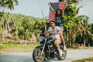 jovem casal dentro amor, equitação uma motocicleta, abraço, paixão, livre espírito, americano bandeira foto