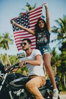 jovem casal dentro amor, equitação uma motocicleta, abraço, paixão, livre espírito, americano bandeira foto