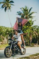 jovem casal dentro amor, equitação uma motocicleta, abraço, paixão, livre espírito, americano bandeira foto