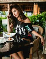 jovem à moda lindo mulher sentado às tropical recorrer cafeteria foto