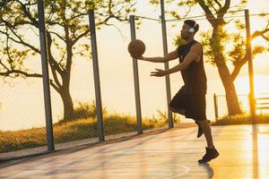 Preto homem fazendo Esportes, jogando basquetebol em nascer do sol, ativo estilo de vida, ensolarado verão manhã foto