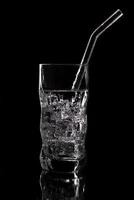 copo de refrigerante de água com gás com gelo no fundo preto foto