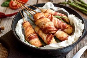 rolo com bacon e frango picado em um guisado com aspargos frescos
