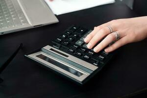 eficiente financeiro gerenciamento. mulher contador usa calculadora e computador portátil, ambos dentro escritório e enquanto trabalhando a partir de casa foto