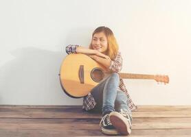 hipster mulher estilo retrato relaxando com guitarra parece tão feliz. foto