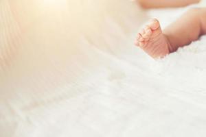 pernas de bebê recém-nascido na cama branca.