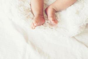 pernas de bebê recém-nascido na cama branca.