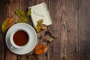 uma xícara de café sobre um livro com folhas secas foto