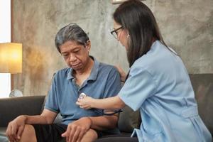 médica, verificando a saúde de paciente idoso asiático do sexo masculino em casa. foto