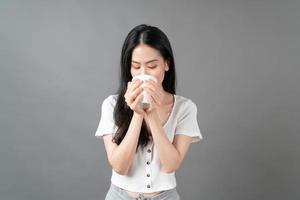 jovem mulher asiática com um rosto feliz e uma mão segurando uma xícara de café foto