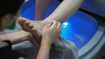 Spa de pés. mulher pés descalços massageando na máquina de água com sabão na loja do spa. foto