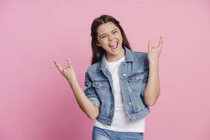 adolescente travessa e alegre mostrando um gesto de pedra com os dedos foto