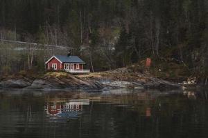 casa de madeira vermelha perto do lago no contexto da floresta foto