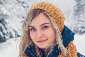 retrato de uma linda garota em um parque de inverno caminhando na floresta de inverno foto