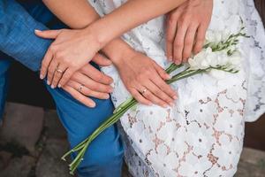 mãos da noiva e do noivo deitam-se sobre um buquê de flores foto