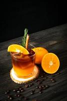 um copo de café preto americano gelado e uma camada de suco de laranja e limão decorado com alecrim e canela foto