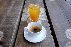 xícara de café e um copo de suco de laranja fresco em uma placa de madeira foto