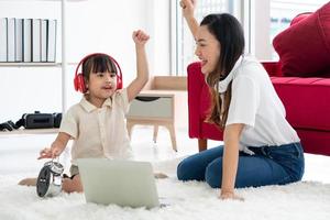 mãe asiática ensinando criança a estudar no computador em casa foto