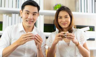 mulher asiática e homem sentados no café tomando café expresso foto