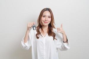 retrato linda mulher asiática segurando a chave do carro no fundo branco