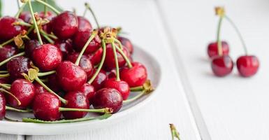 Frescas deliciosas bagas vermelhas brilhantes de cereja rasgadas no jardim de verão foto