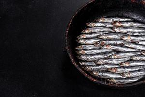 vários peixes salgados de anchovas em uma mesa escura de concreto foto