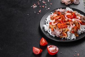 macarrão de arroz saboroso com tomate, pimenta vermelha, cogumelos e frutos do mar foto