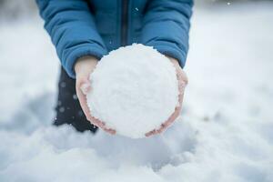 pessoa segurando uma bola de neve dentro a neve. generativo ai foto