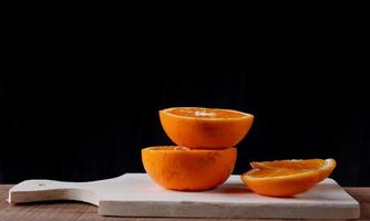 fatias de laranja em uma tábua de madeira em fundo preto foto