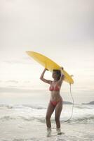 surfista menina com dela prancha de surfe em a de praia. foto