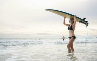 surfista menina com dela prancha de surfe em a de praia. foto