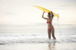 surfista menina com dela prancha de surfe em a de praia. foto