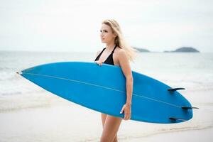 surfista menina com dela prancha de surfe em a de praia. foto