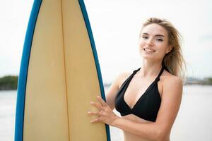 surfista menina com dela prancha de surfe em a de praia. foto