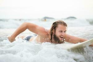 jovem homem surfar em a de praia tendo Diversão e balanceamento em a prancha de surfe foto