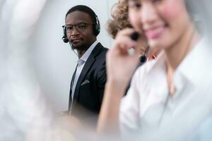 grupo do o negócio pessoas vestindo fone de ouvido trabalhando ativamente dentro escritório. ligar Centro, telemarketing, cliente Apoio, suporte agente providenciar serviço em Telefone vídeo conferência chamar. foto