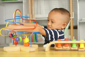 Garoto jogando com desenvolvimentista brinquedos em mesa às casa foto