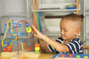 Garoto jogando com desenvolvimentista brinquedos em mesa às casa foto