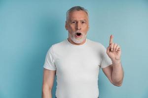 o homem mais velho está gesticulando em um fundo azul foto