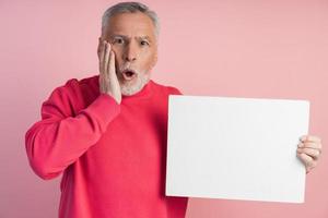 surpreendeu o homem sênior segurando uma folha de papel branca. isolado foto