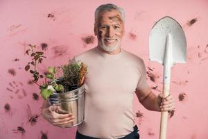 homem sênior, jardineiro com uma pá e um balde nas mãos foto