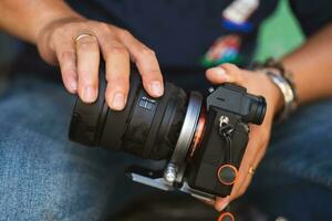 masculino mãos colocando em moderno digital Câmera profissional lente foto
