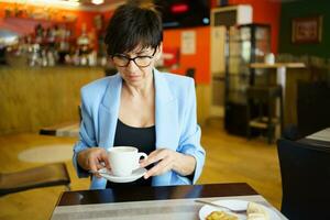 pensativo mulher com copo do café dentro cafeteria foto